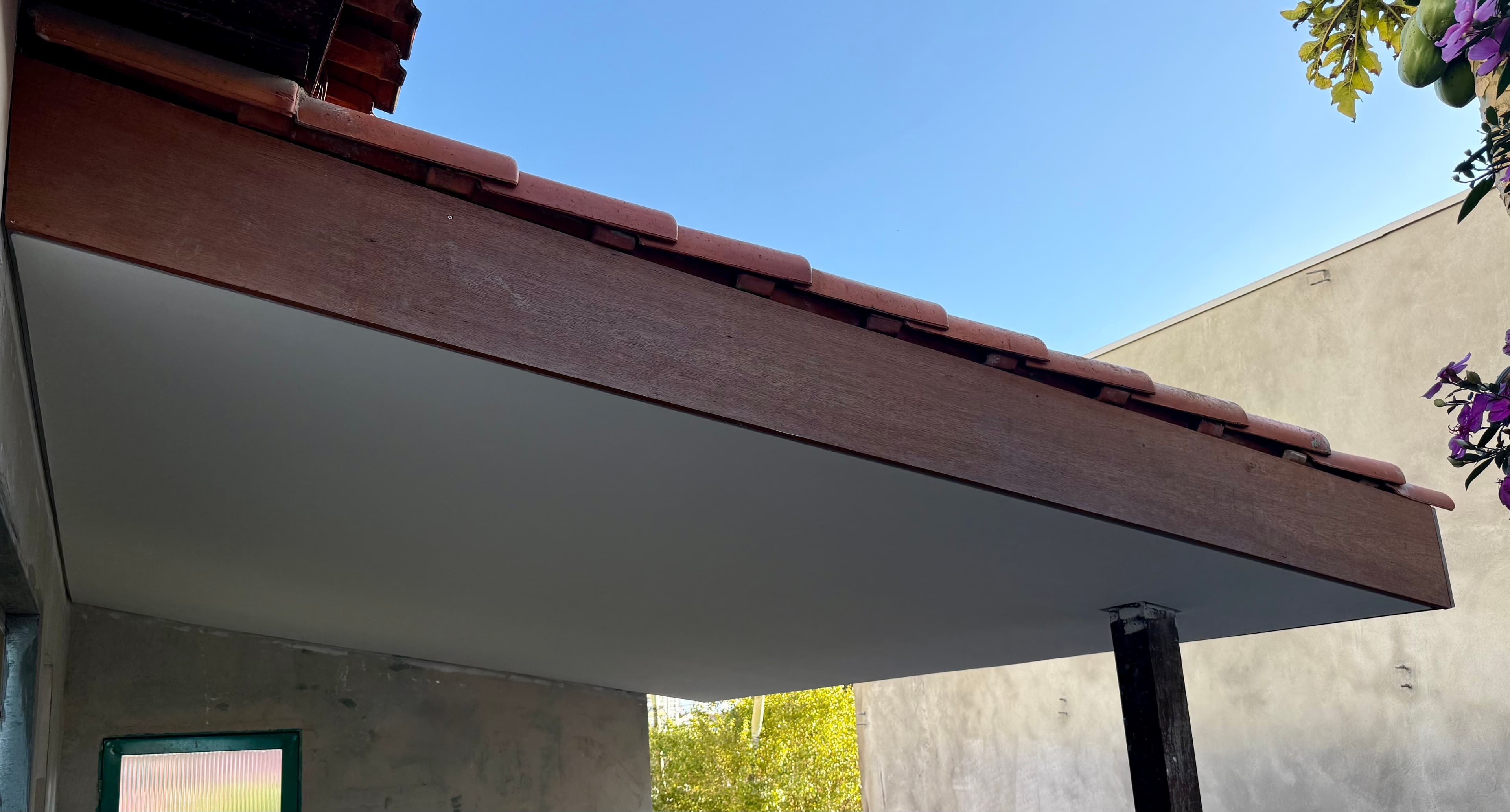 Forro de drywall instalado no beiral externo da casa, sob as telhas, com céu azul ao fundo.